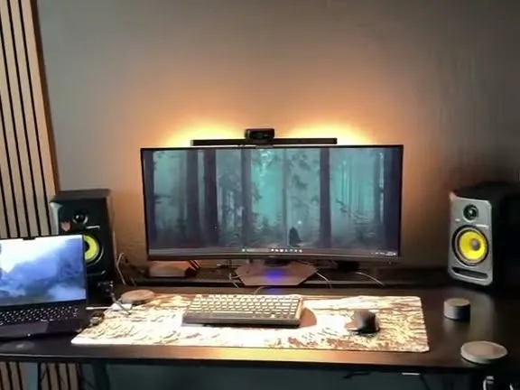 Emmanuel's desk: ultrawide monitor with a warm light bar, speakers, and a laptop